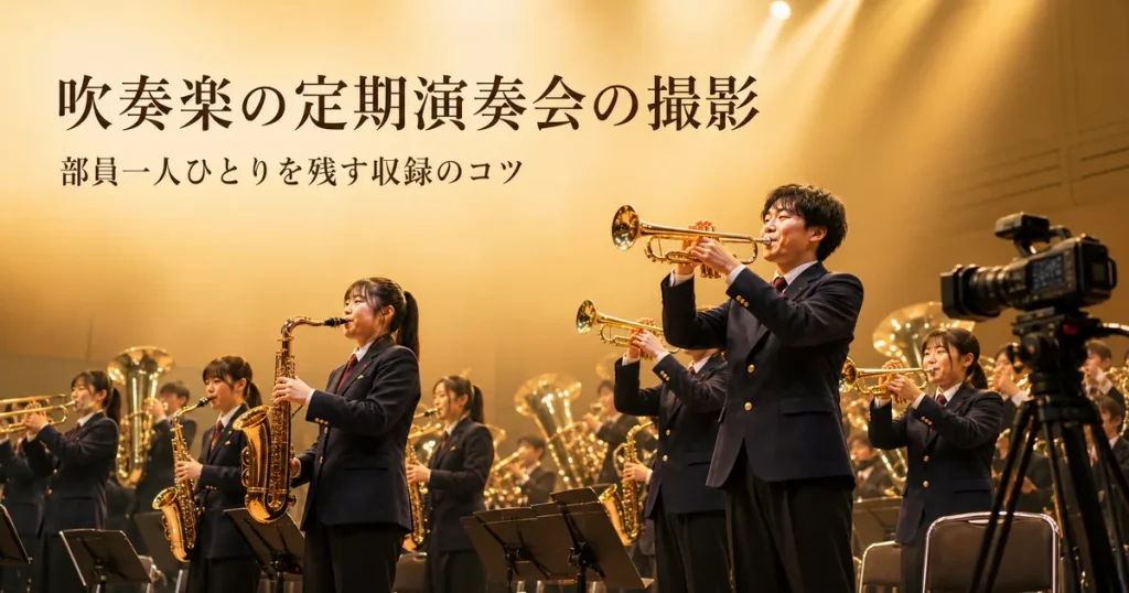 ステージで演奏する吹奏楽団と、それを撮影するビデオカメラ